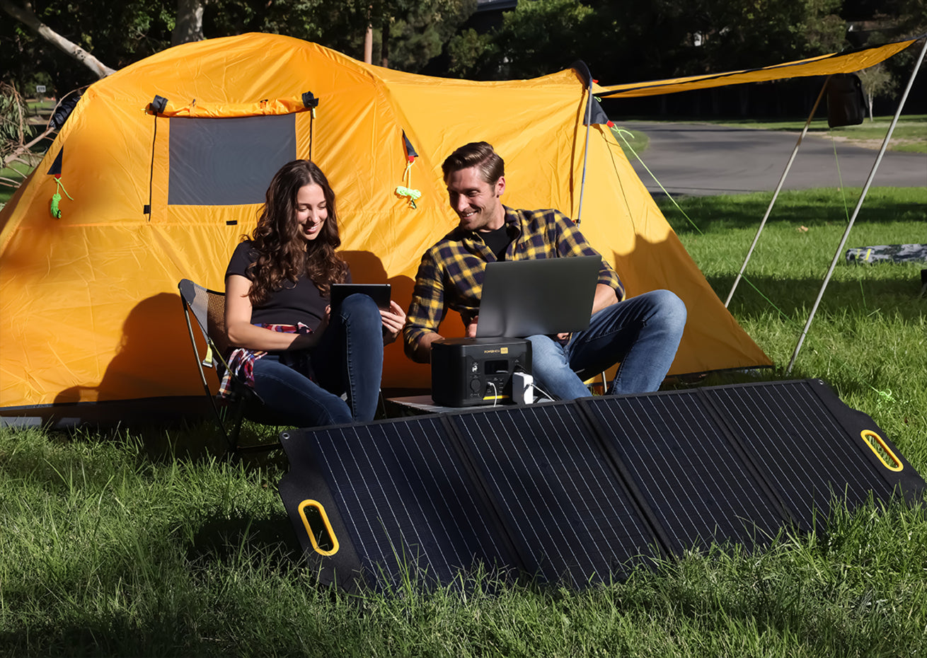 Powerness Hiker U1000: Couple charging power station outdoors with solar panel, connecting electronics for portable energy. Battery Power Station