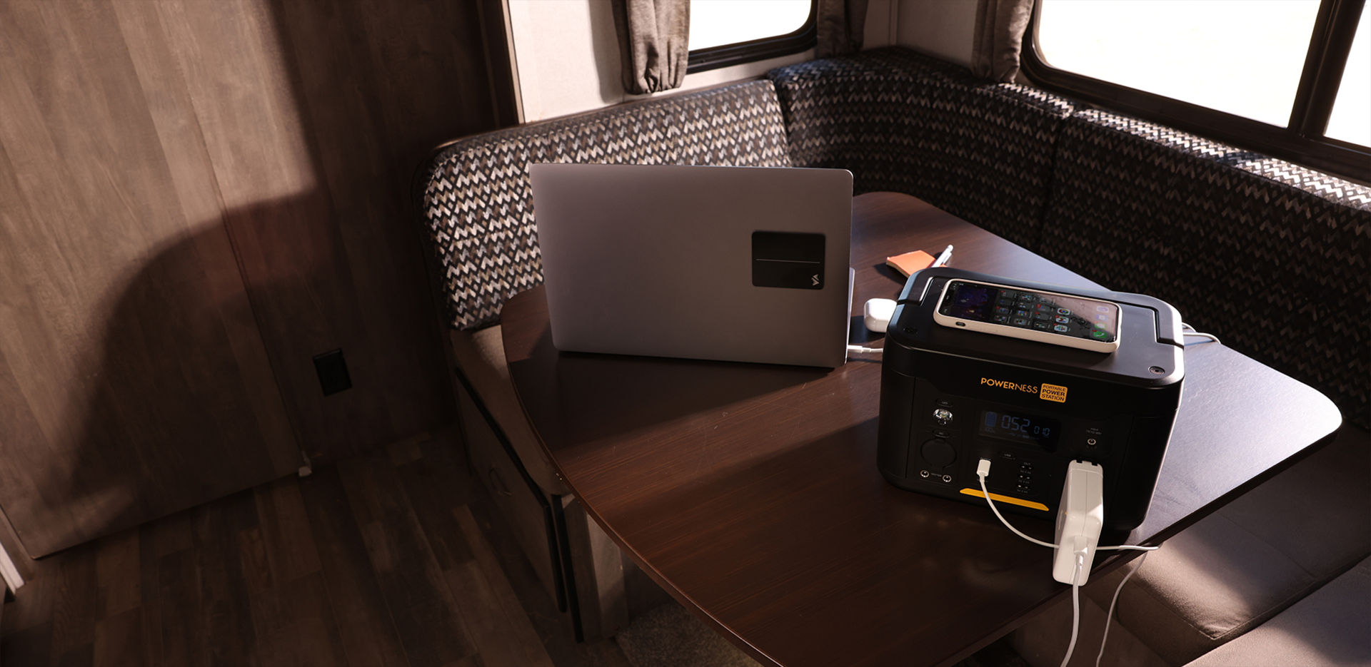 Powerness Hiker U1000: Power station placed on RV dining table, providing laptop charging and convenient power source on the go. Backup Solar Generator