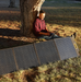Powerfulness SolarX S200: Man outdoors, using laptop powered by solar panel amidst nature. Portable Solar Panels For Camping